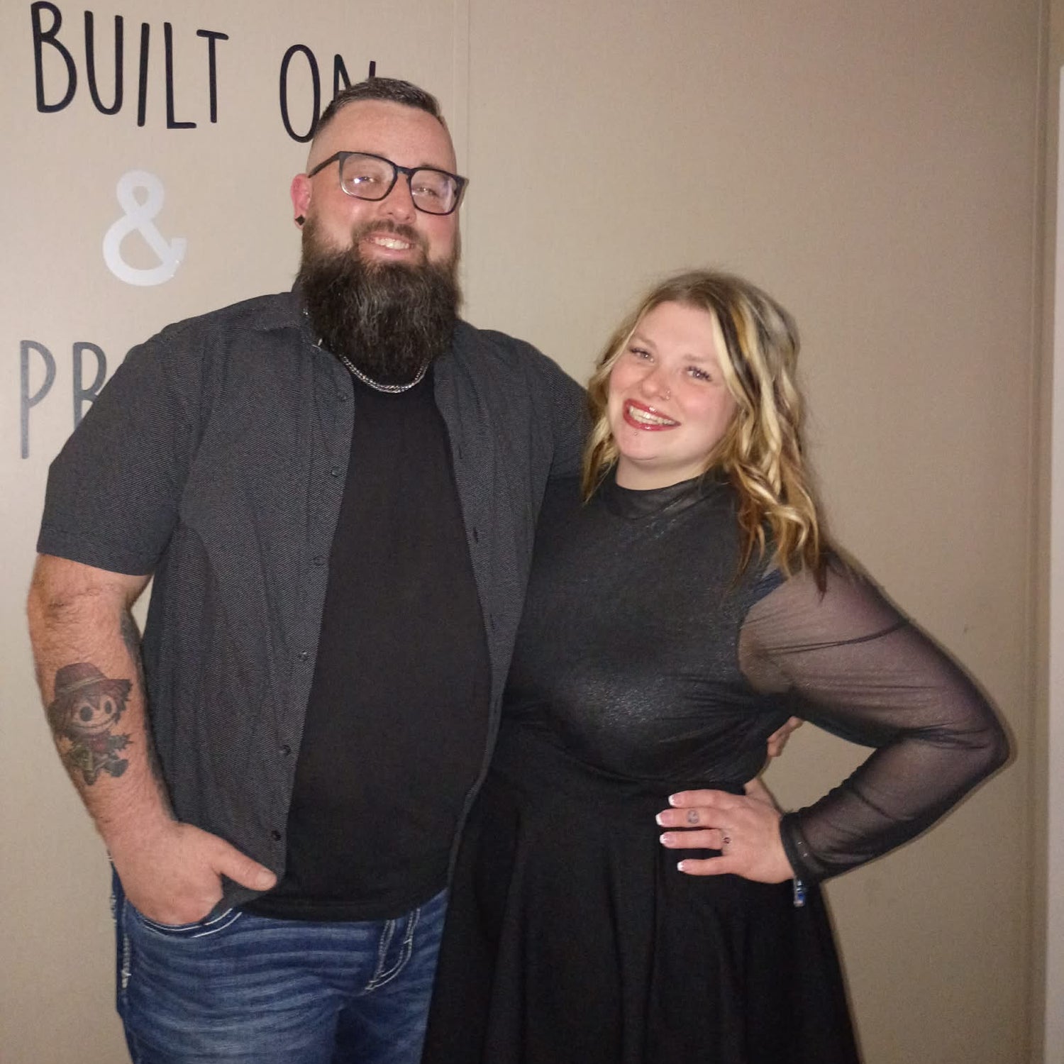Two people standing together against a wall with text on it.